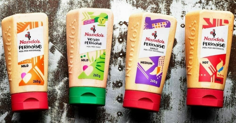 Four tubes of Nando's Perinaise on a wooden surface.