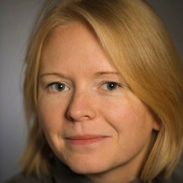 Blond hair, gray shirt.