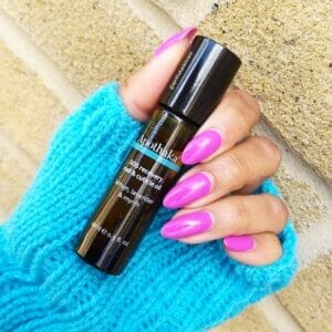 A hand holding a bottle of essential oil.