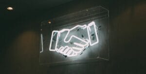A neon sign with a handshake on it.